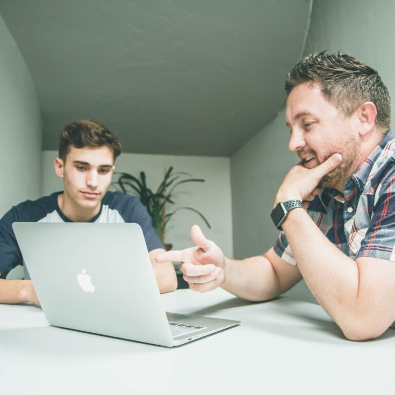 Man and younger man discussion over laptop