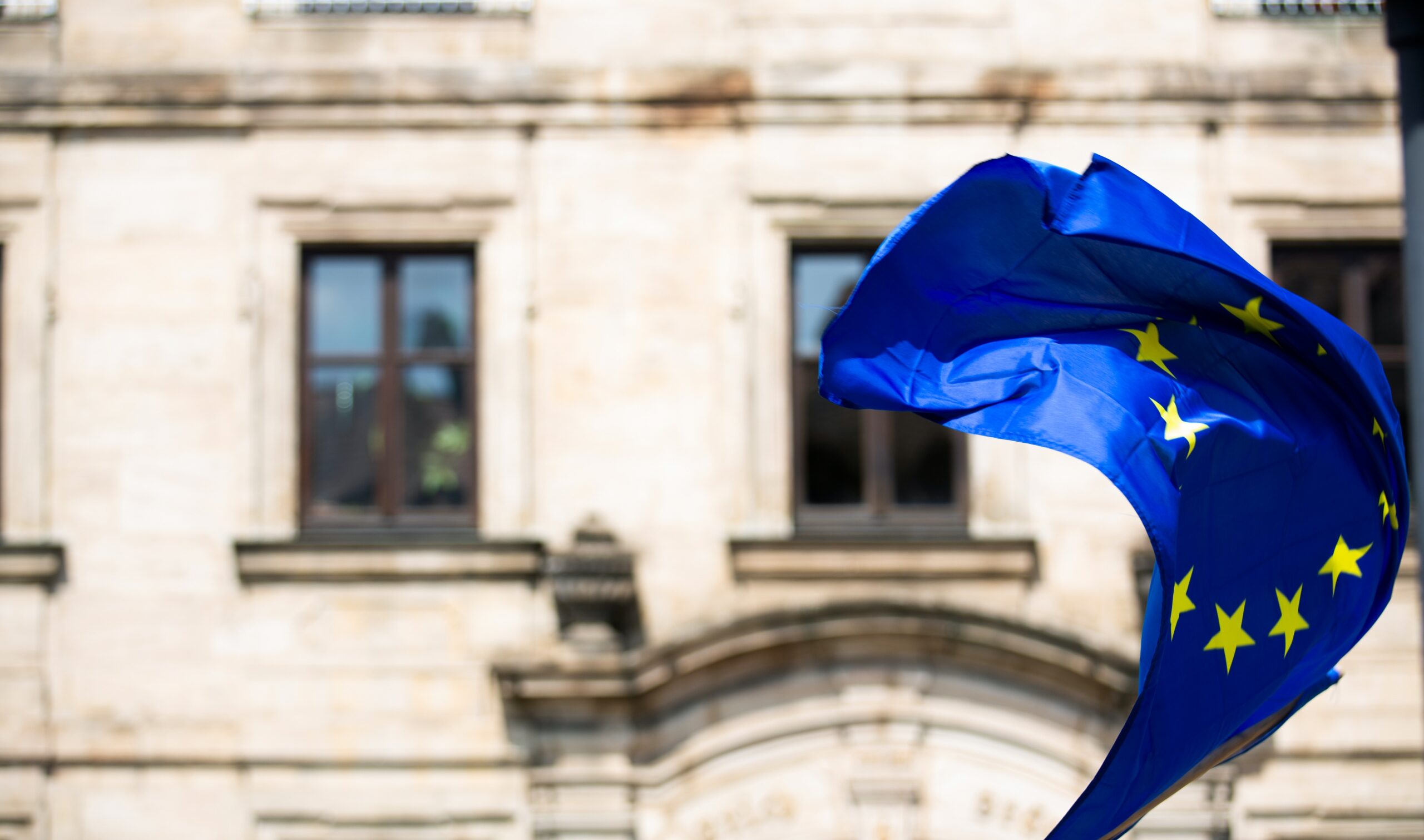 EU flag blowing in the wind in front of building