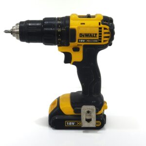 Black and yellow power drill standing on a white surface.