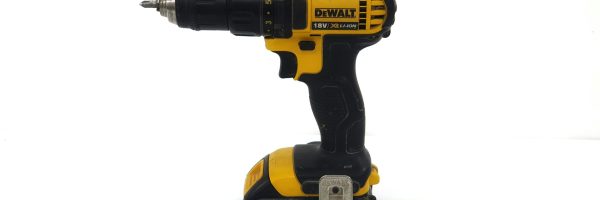 Black and yellow power drill standing on a white surface.